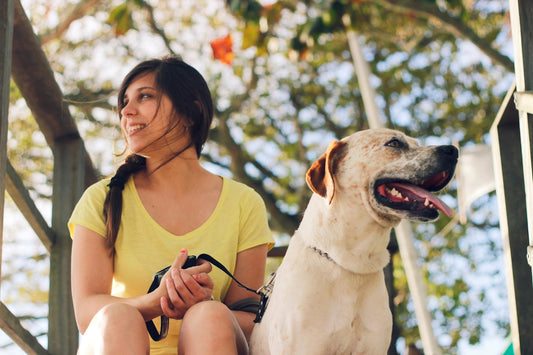 woman in yellow tank top sitting beside white short coated dog